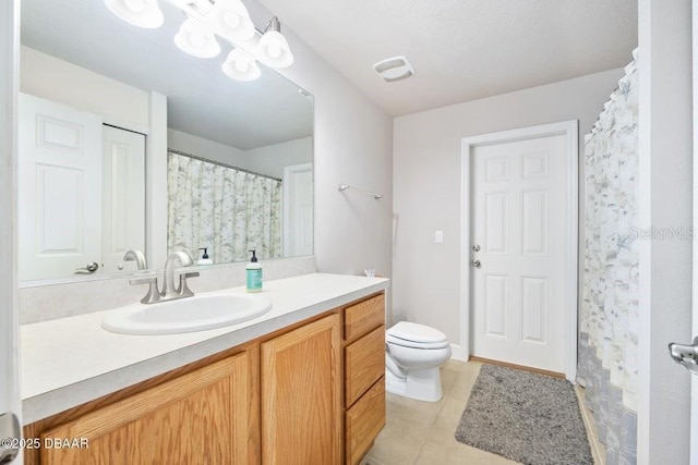 bathroom with toilet, vanity, and tile patterned flooring