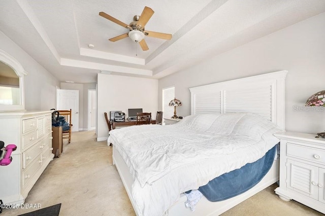 carpeted bedroom with ceiling fan and a tray ceiling