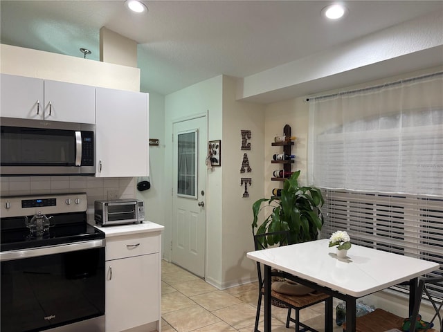 kitchen featuring white cabinets, stainless steel appliances, backsplash, and light tile patterned floors