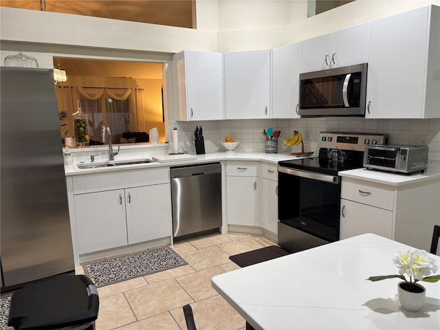 kitchen with sink, stainless steel appliances, light tile patterned flooring, and white cabinetry