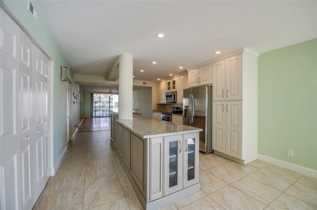 kitchen with ornate columns, kitchen peninsula, appliances with stainless steel finishes, white cabinets, and light stone counters