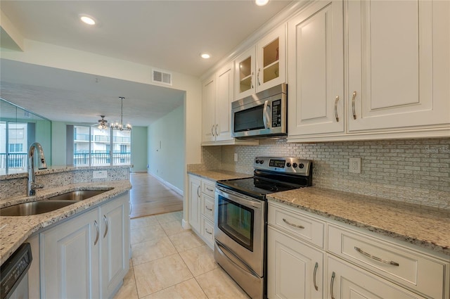 kitchen featuring white cabinets, stainless steel appliances, sink, light stone counters, and light tile patterned floors