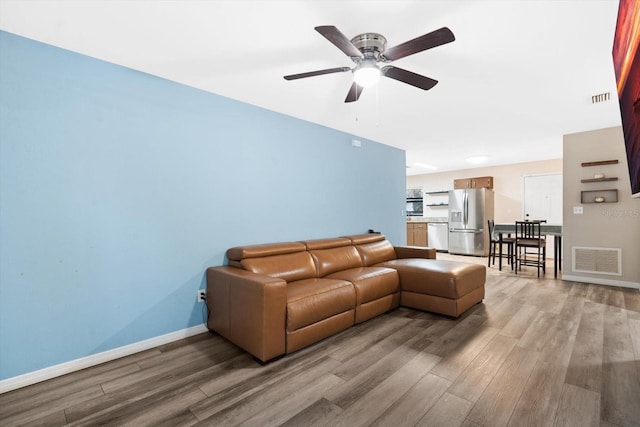 living room featuring ceiling fan and light hardwood / wood-style flooring