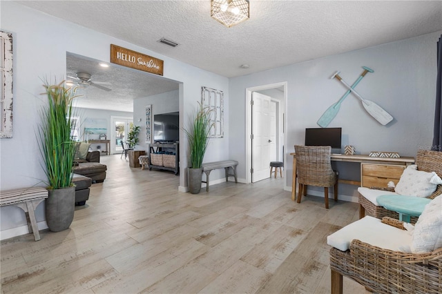 home office with ceiling fan, a textured ceiling, and light wood-type flooring