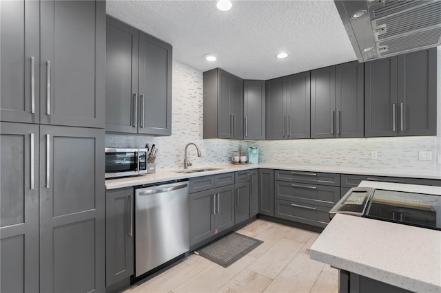 kitchen featuring gray cabinets, stainless steel appliances, backsplash, light hardwood / wood-style flooring, and sink