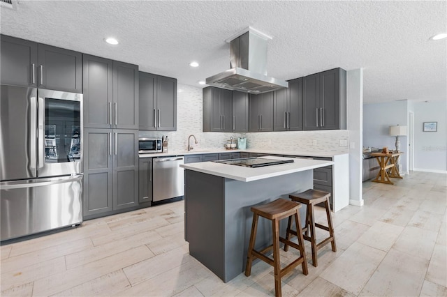 kitchen featuring tasteful backsplash, sink, appliances with stainless steel finishes, a kitchen breakfast bar, and island range hood