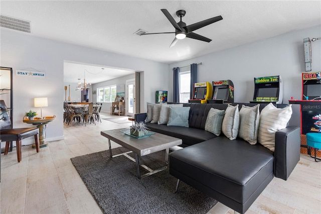 living room with light wood-type flooring and ceiling fan with notable chandelier