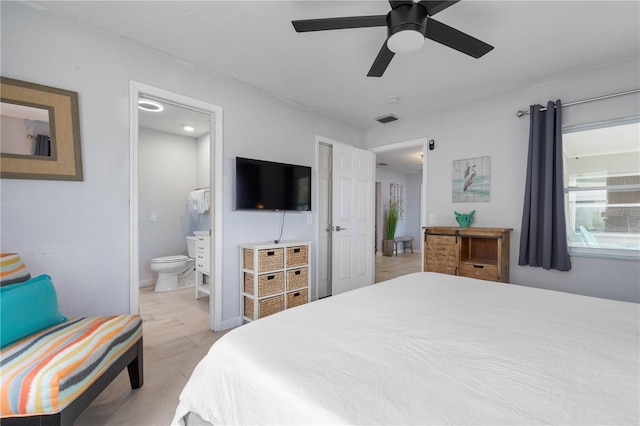 bedroom with light wood-type flooring, ceiling fan, and connected bathroom