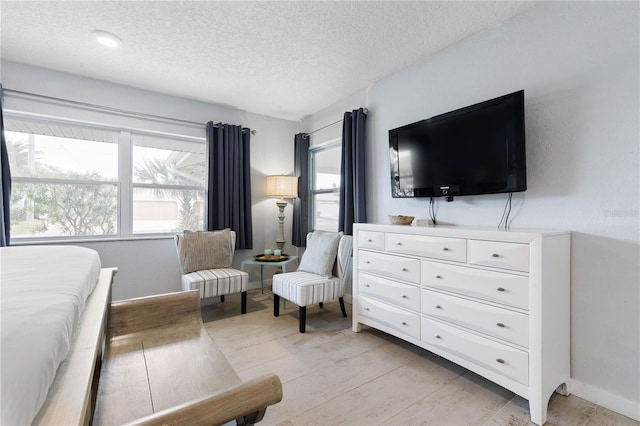 bedroom featuring a textured ceiling and light hardwood / wood-style floors