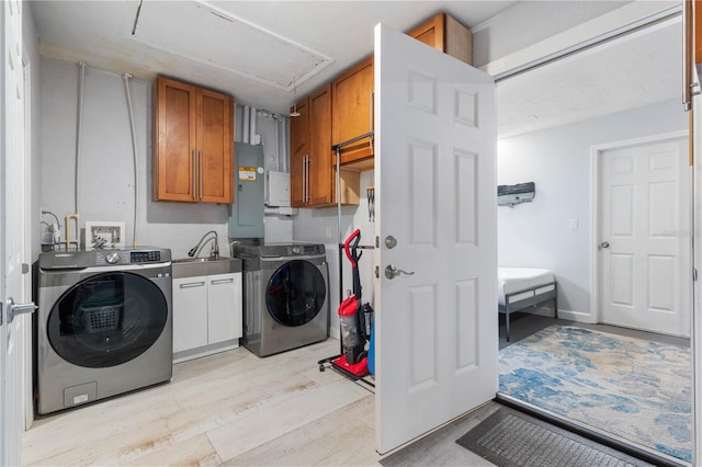 washroom featuring washing machine and dryer, cabinets, electric panel, light hardwood / wood-style flooring, and sink