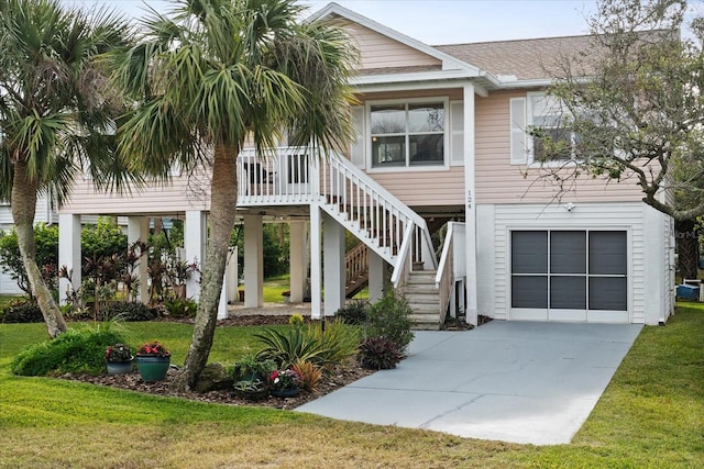 coastal inspired home with a garage and a front lawn