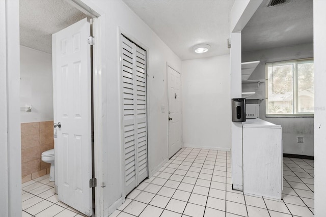 kitchen with washer / clothes dryer, tile walls, a textured ceiling, and light tile patterned flooring