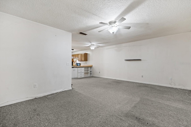 unfurnished living room with a textured ceiling, ceiling fan, and carpet