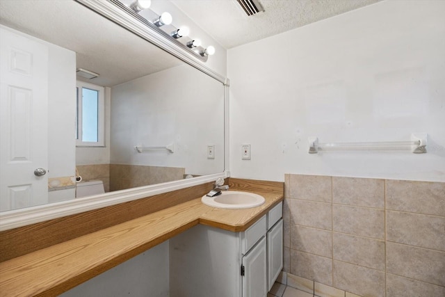 bathroom with a textured ceiling, toilet, tile patterned floors, and vanity