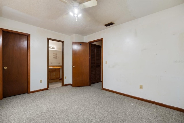 unfurnished bedroom with carpet, a textured ceiling, ensuite bath, a closet, and ceiling fan