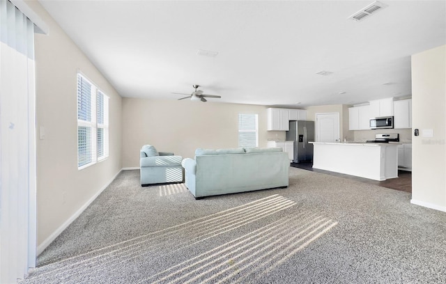 unfurnished living room with ceiling fan and dark carpet