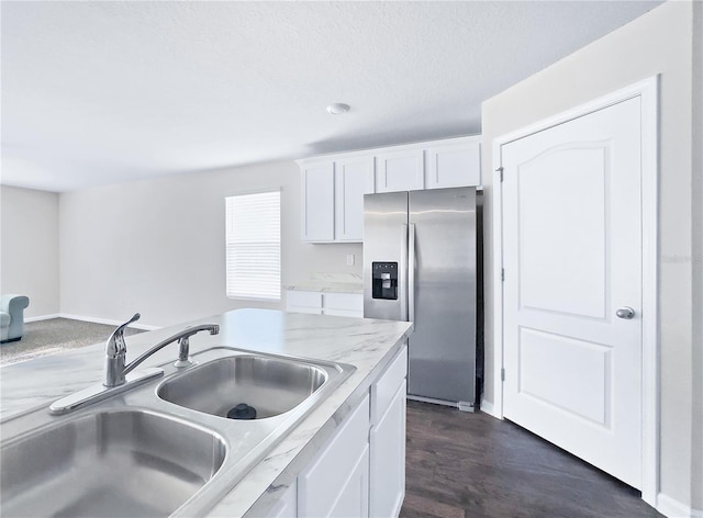 kitchen with sink, dark hardwood / wood-style floors, stainless steel fridge, light stone countertops, and white cabinets