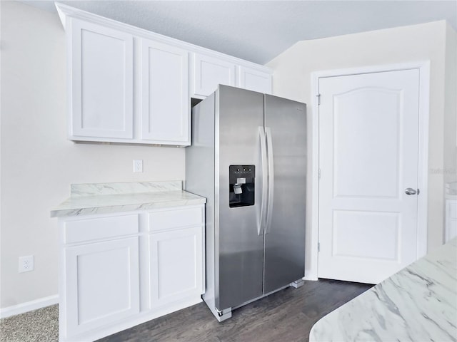 kitchen featuring light stone counters, dark wood-type flooring, stainless steel fridge, and white cabinets