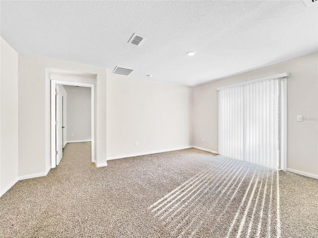 spare room featuring carpet flooring and a textured ceiling