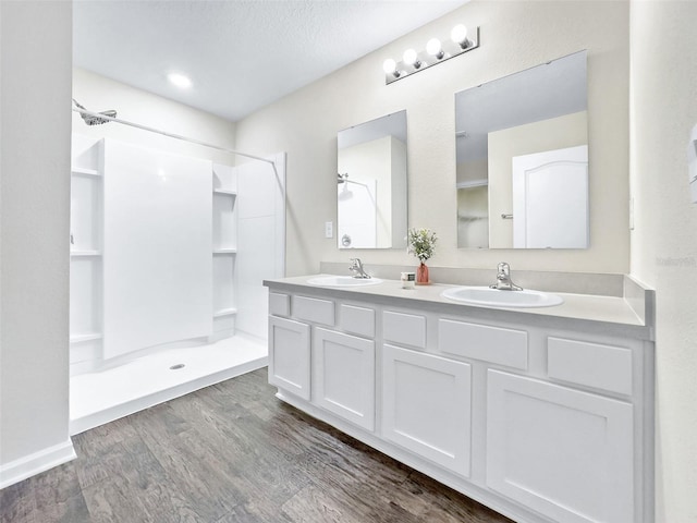 bathroom with hardwood / wood-style flooring, vanity, a textured ceiling, and walk in shower