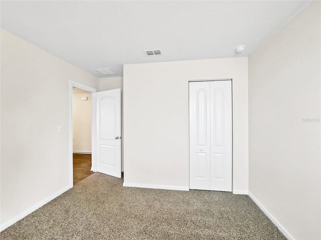 unfurnished bedroom with dark carpet and a closet