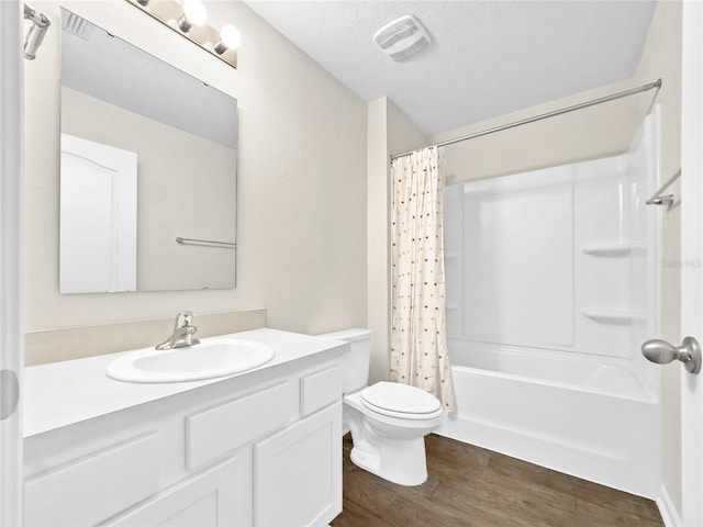 full bathroom featuring wood-type flooring, shower / bath combination with curtain, vanity, toilet, and a textured ceiling