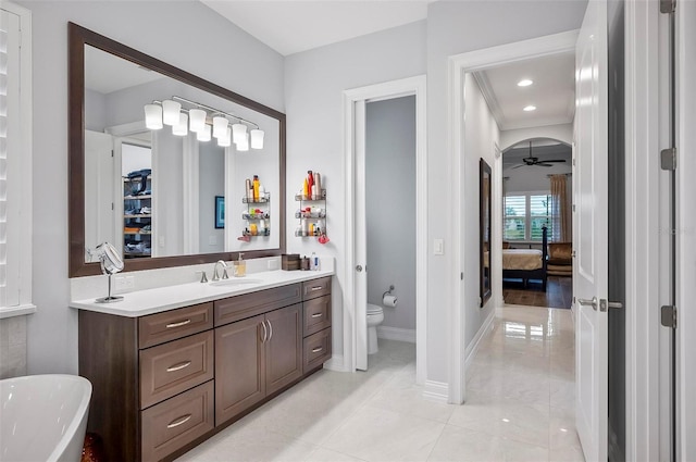 bathroom featuring toilet, crown molding, vanity, ceiling fan, and a washtub