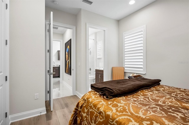 bedroom with radiator, hardwood / wood-style floors, and ensuite bath