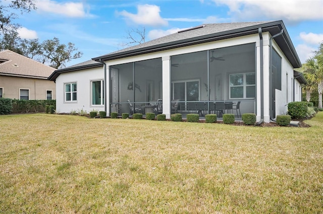 rear view of property with ceiling fan, a yard, and a sunroom