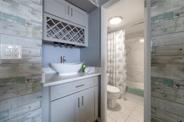 full bathroom with toilet, wooden walls, shower / tub combo with curtain, tile patterned floors, and vanity