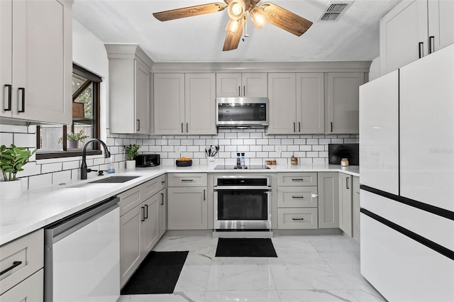 kitchen with stainless steel appliances, sink, ceiling fan, decorative backsplash, and gray cabinets