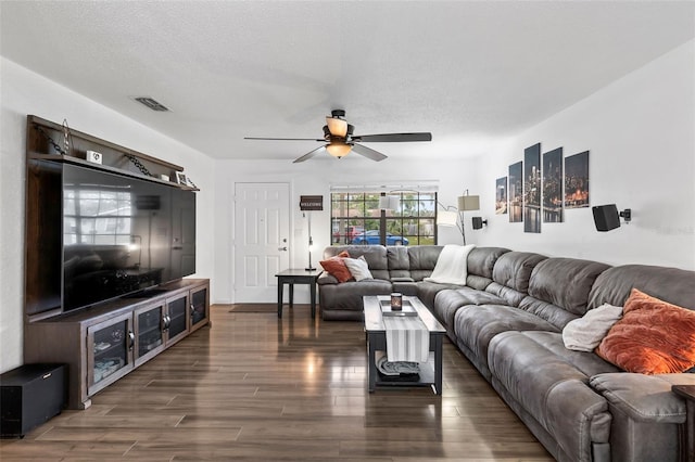 living room with ceiling fan, dark wood-type flooring, and a textured ceiling