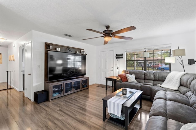 living room featuring hardwood / wood-style flooring, a textured ceiling, and ceiling fan