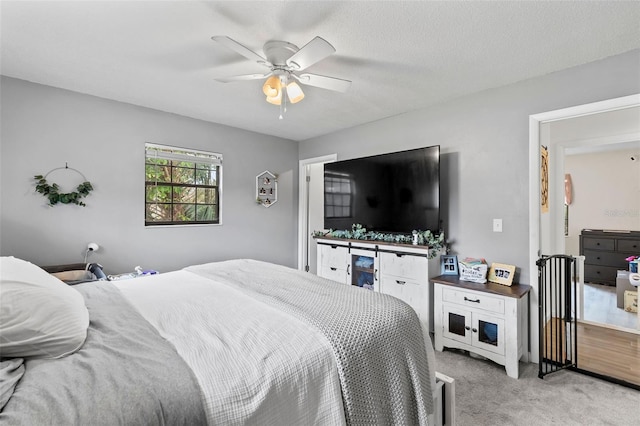 bedroom with ceiling fan, light colored carpet, and a textured ceiling