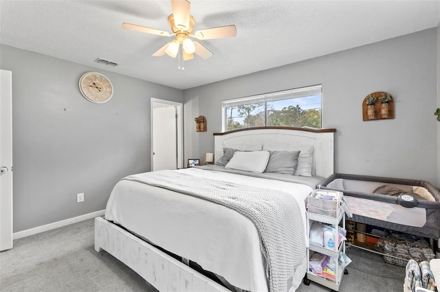 carpeted bedroom with ceiling fan and a textured ceiling