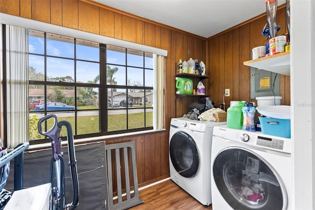 clothes washing area featuring independent washer and dryer, wooden walls, a wealth of natural light, and hardwood / wood-style floors