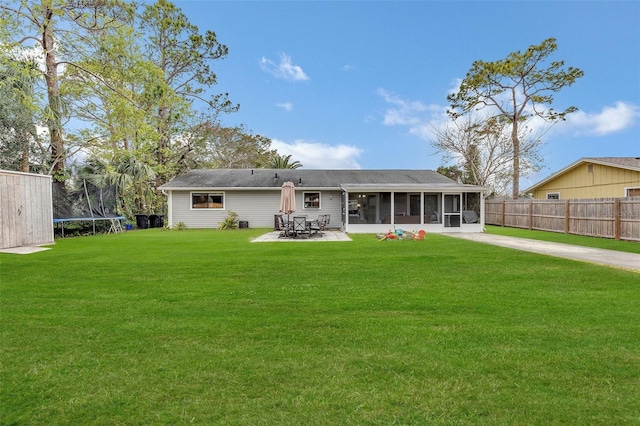 rear view of house featuring a patio, a yard, a sunroom, and a trampoline