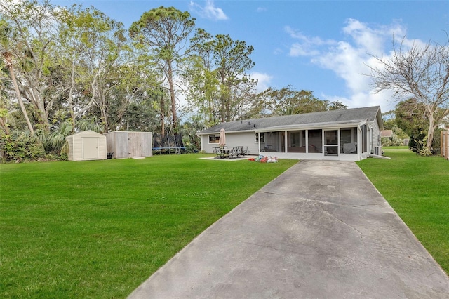 rear view of property featuring a patio, a sunroom, a trampoline, a lawn, and a shed