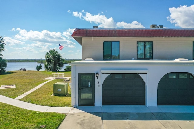 view of front of house with a garage, a water view, and a front yard