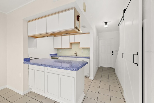 kitchen with white cabinetry, a barn door, light tile patterned flooring, and sink