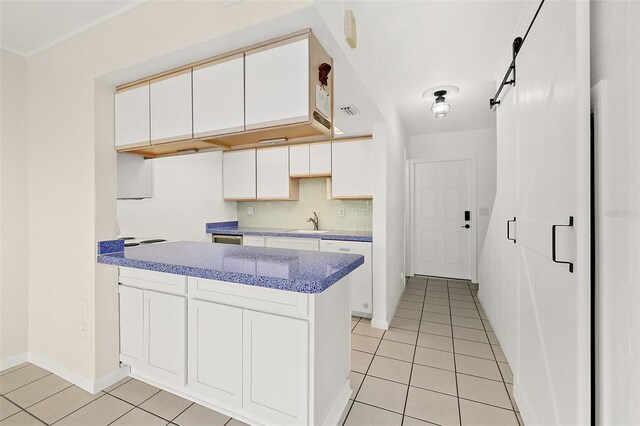 kitchen with sink, a barn door, white cabinets, and light tile patterned flooring