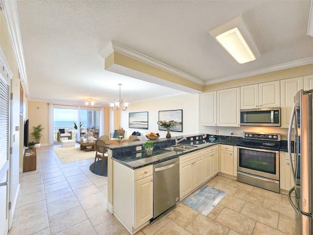 kitchen featuring dark stone counters, kitchen peninsula, stainless steel appliances, crown molding, and an inviting chandelier