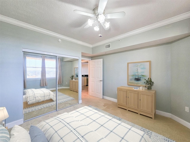 carpeted bedroom featuring ceiling fan, crown molding, a closet, and a textured ceiling