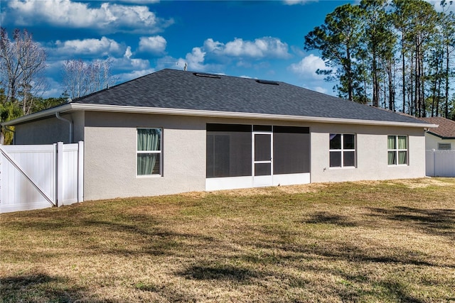 back of house with a sunroom and a lawn