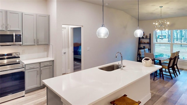 kitchen with gray cabinetry, sink, hanging light fixtures, and appliances with stainless steel finishes