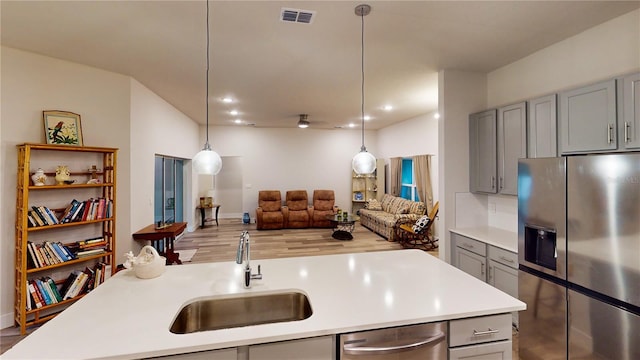 kitchen featuring pendant lighting, appliances with stainless steel finishes, gray cabinets, and sink