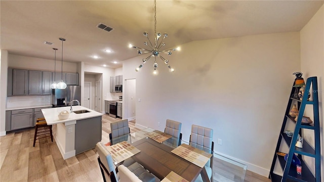 dining room with lofted ceiling, sink, a notable chandelier, and light wood-type flooring