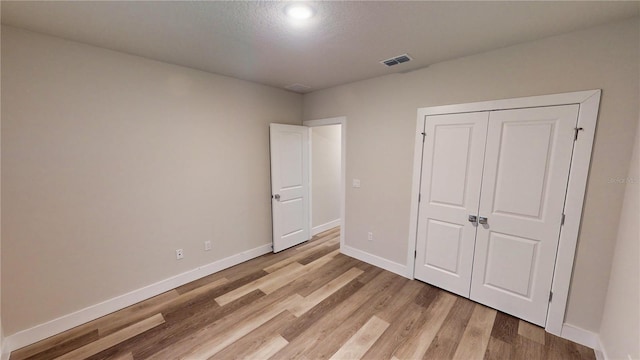 unfurnished bedroom with light hardwood / wood-style flooring and a closet