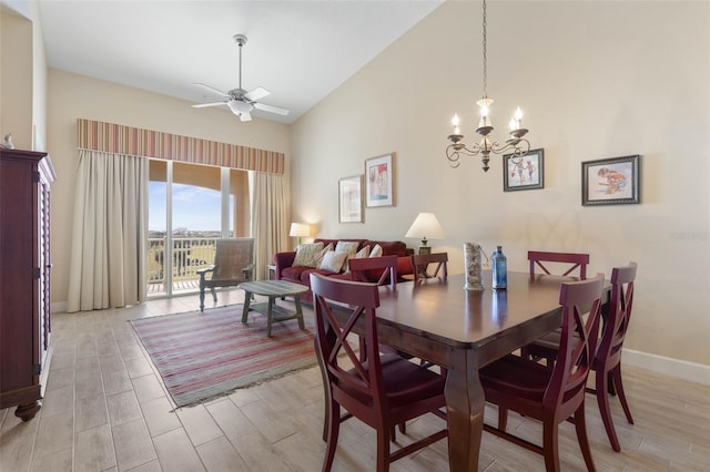 dining space featuring ceiling fan with notable chandelier, high vaulted ceiling, and light wood-type flooring