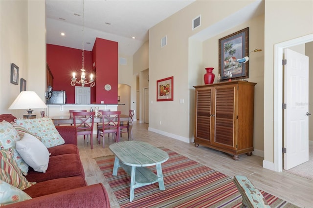 living room with a notable chandelier, high vaulted ceiling, and light hardwood / wood-style flooring